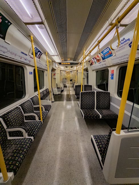 Inside Hackney Central station, the image showcases a modern, high-speed train with a sleek white exterior and a red stripe along the side, positioned on a clean, well-maintained platform. The station features an expansive glass and steel arched roof allowing natural light to illuminate the area. The platform's surface appears smooth and free of dust or debris, with visible markings and signs guiding passengers. Nearby, a clock displays the current time, and there are minor elements like benches and waste bins visible. The overall scene highlights the station's hygienic and orderly condition, emphasizing the importance of surface cleaning and maintenance for public spaces. Carpet Cleaners E5 is committed to delivering professional sanitisation and deep cleaning solutions for commercial environments such as train stations, ensuring hygiene and safety for commuters.